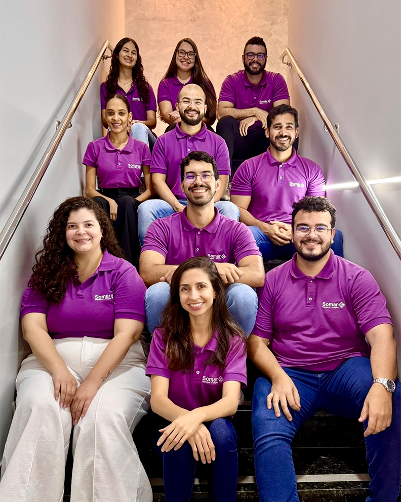 Equipe da Somar Engenharia em uma escada, utilizando o uniforme roxo.